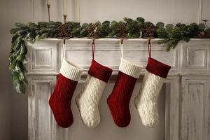 Close-up of four knitted Christmas stockings in red and white on a wooden fireplace