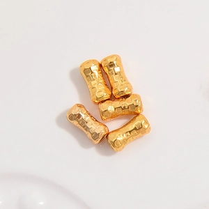 Detailed view of five textured gold hammered bamboo style beads on white background