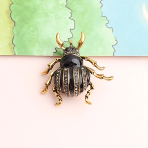 Macro detail of beetle brooch showing black enamel finish and sparkling crystal inlays