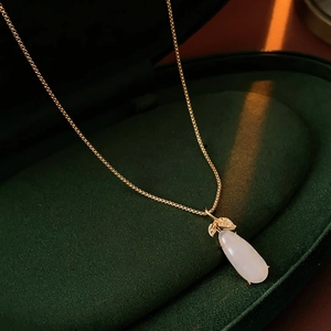Detailed close-up of a white teardrop gemstone pendant on a gold micro-set zircon chain