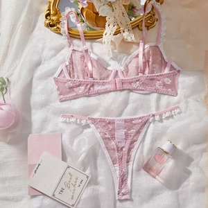 Pink lace lingerie set with floral embroidery and underwire bra on white fabric