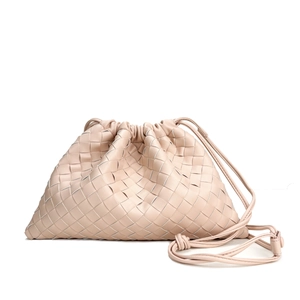 Pink woven leather shoulder bag with drawstring closure and crossbody strap on white background
