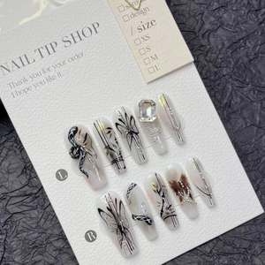 Handmade press-on nails with butterfly and snake patterns, accented with sequins and rhinestones