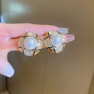 Close-up of vintage gold pearl earrings with black enamel and sparkling rhinestones