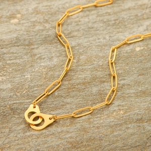 Chic golden stainless steel cross chain necklace featuring unique handcuff pendant on rock