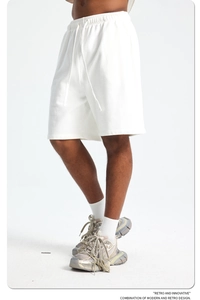 Detail of white cotton sweatshorts with drawstring waist and retro athletic sneakers