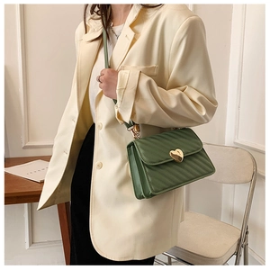 Detail of green pleated crossbody bag featuring a golden heart lock and diamond stitching