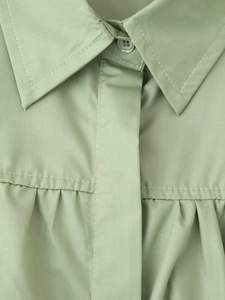 Detail of sage green cotton shirt showing pleated texture and neat buttons