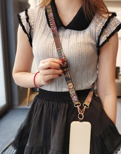 Detail of adjustable crossbody phone strap with colorful geometric totem pattern and metal buckles
