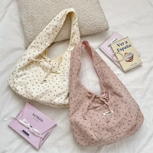 Close-up of floral corduroy tote bags in beige and pink with decorative bow details