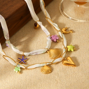 Détail du collier ruban de soie avec breloques coquillages dorés et étoiles de mer