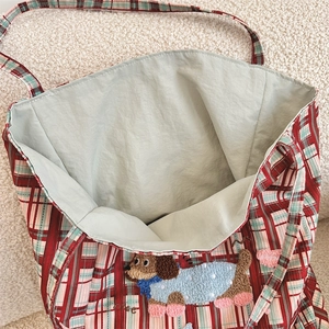 Detail of checkered canvas tote bag featuring a cute dachshund embroidery and spacious interior