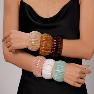 Gros plan d'un mannequin portant six bracelets joncs en résine acrylique texturée rétro