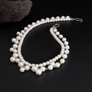 Double-layered pearl waist chain with cross charms and silver carabiner on volcanic rock