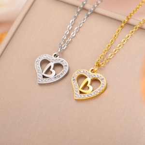 Macro shot of gold and silver heart pendants with letter B and white zircon stones