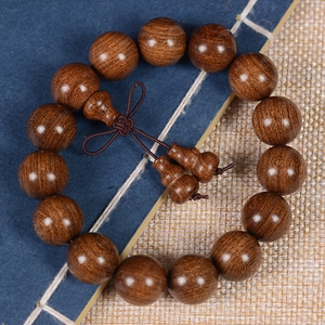 Detailed view of 15 brown sandalwood prayer beads with traditional Chinese knot on a mat