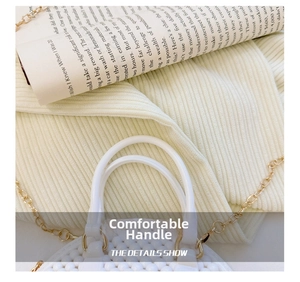 Detail of white beaded shell bag featuring a smooth handle and golden metal chain strap