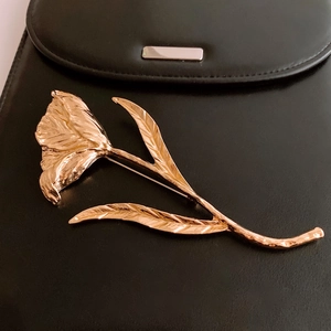 Detailed close-up of golden tulip brooch showing textured petals and leaf veins