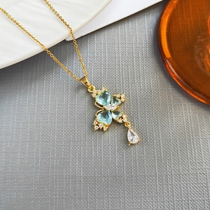 Elegant gold butterfly necklace with blue zircon stones on textured gray background