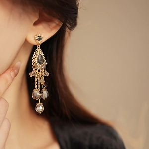 Detailed close-up of bohemian chandelier earrings with smoky crystals and golden tassels