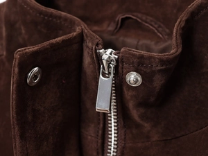 Detailed macro view of silver metal zipper and snap buttons on brown suede jacket