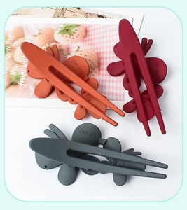 Three matte butterfly hair clips in orange, burgundy, and dark grey with model TCB-427