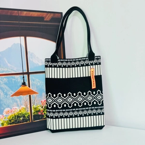 Detail of knit tote bag featuring black and white geometric ethnic patterns and red tag