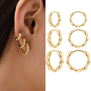 Detail showing three pairs of golden twisted hoop earrings for stacked wearing styles