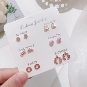 Close-up of six pairs of rose gold pearl stud earrings on a weekly mood display card