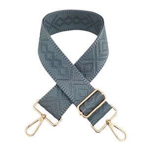Detail of adjustable gray-blue bag strap with geometric diamond weave and gold hooks