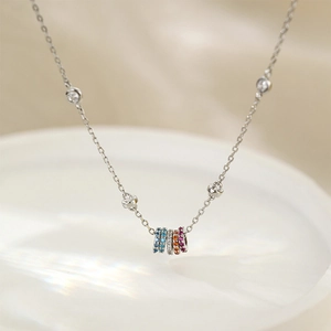 Macro shot of silver geometric necklace featuring five colorful micro-set zircon rings