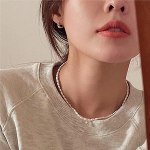 Detailed view of rice pearl necklace and textured gold hoop earrings on a model