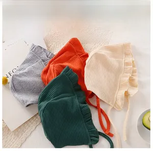 Dettaglio di cappellini in maglia per neonati con bordi a volant e lacci in quattro colori