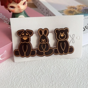Detail view of three cute brown and gold animal hair clips on white cardstock