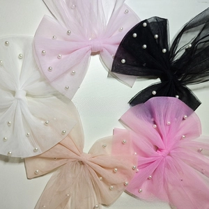 Detail of handcrafted tulle bow hairpins with faux pearl accents in multiple colors