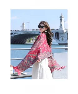 Close-up of red paisley patterned ethnic shawl scarf with fringe details in outdoor setting