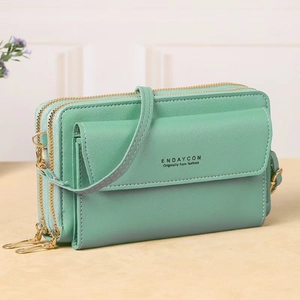 Detail view of mint green faux leather crossbody bag with three golden zipper compartments