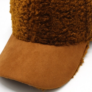 Detailed macro view of brown teddy fleece fabric and beige suede brim on baseball cap