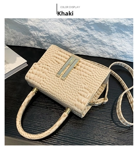 Close-up of khaki crocodile embossed handbag featuring a gold H-shaped metal clasp