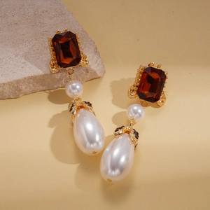 Macro detail of red rectangular gemstone and teardrop pearl on vintage gold earrings