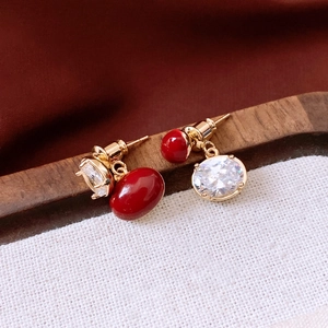 Vue macro de boucles d'oreilles vintage dorées avec perles rouges et pierres de zircon
