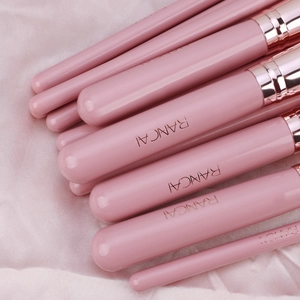 Detail of pink makeup brush handles with rose gold ferrules and logo on silk fabric