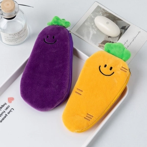 Cute plush vegetable pencil cases featuring smiling eggplant and carrot designs on a tray