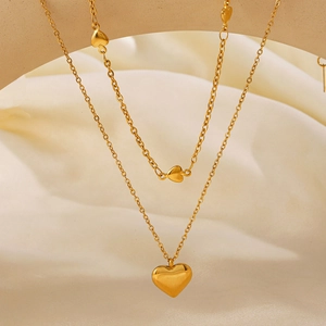 Élégant collier doré à deux rangs avec pendentif cœur sur un fond de soie douce