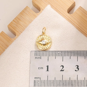 Macro shot of gold sunburst evil eye pendant with cubic zirconia and cm size ruler