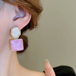 Nahaufnahme eleganter quadratischer und ovaler Marmor-Resin-Ohrringe in Rosa und Creme