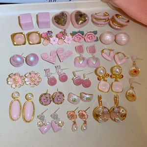 Dettaglio flat lay di un set di gioielli rosa con orecchini a lobo floreali in resina