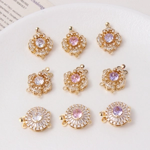 Golden flower jewelry clasps with colorful zircons and pearls displayed on white ceramic