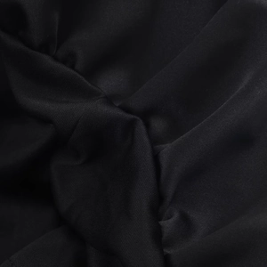 Detailed macro view showing the smooth black fabric texture and fine pleated drape of the dress