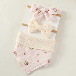 Detailed view of floral cotton baby bib and bow headbands set on presentation card